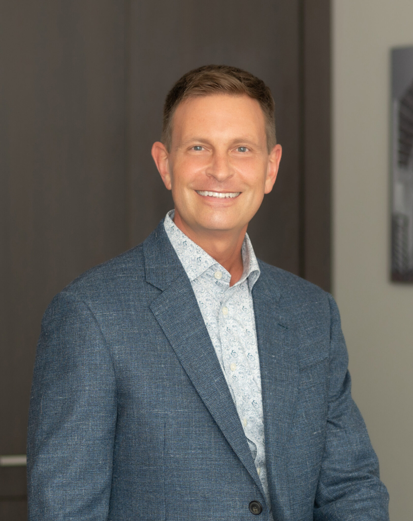 a man wearing a suit and tie smiling at the camera