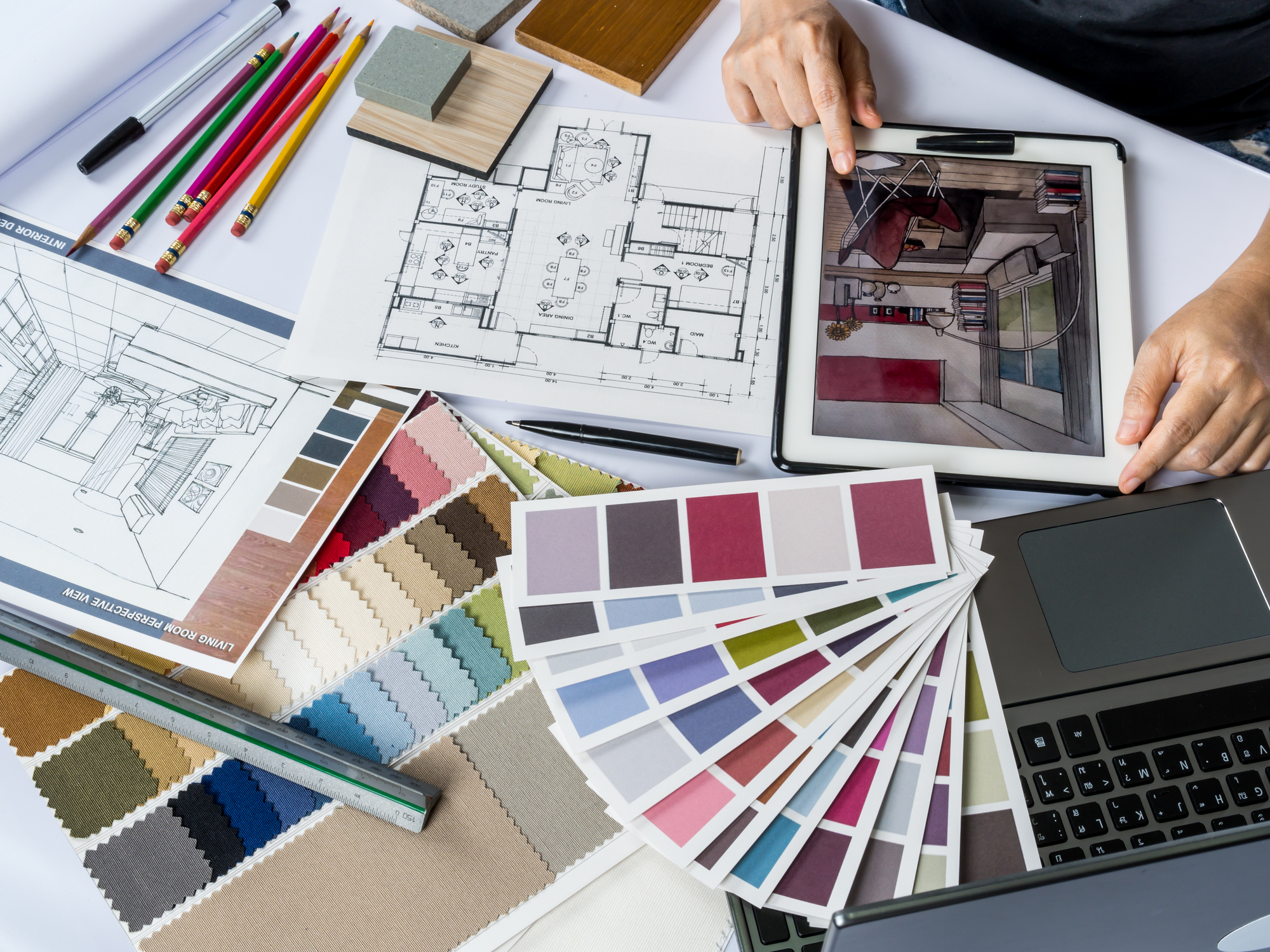 A person planning their interior remodel with color palettes and blueprints.